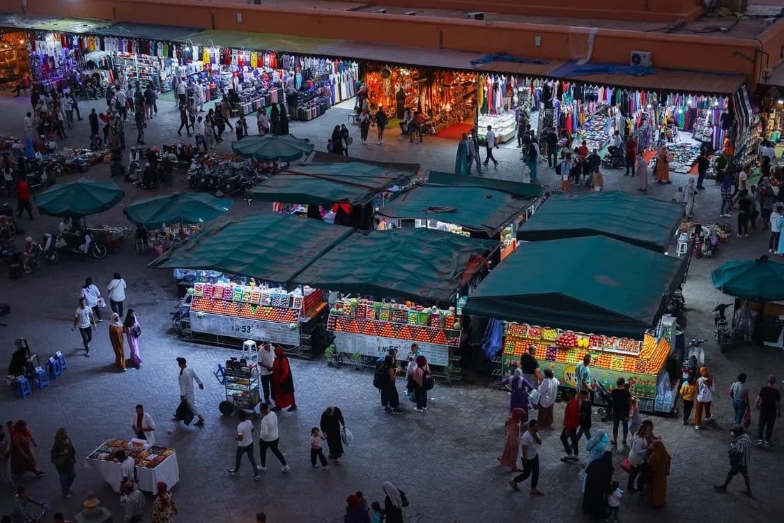A night market seen from above, rows of stalls under green canopies
