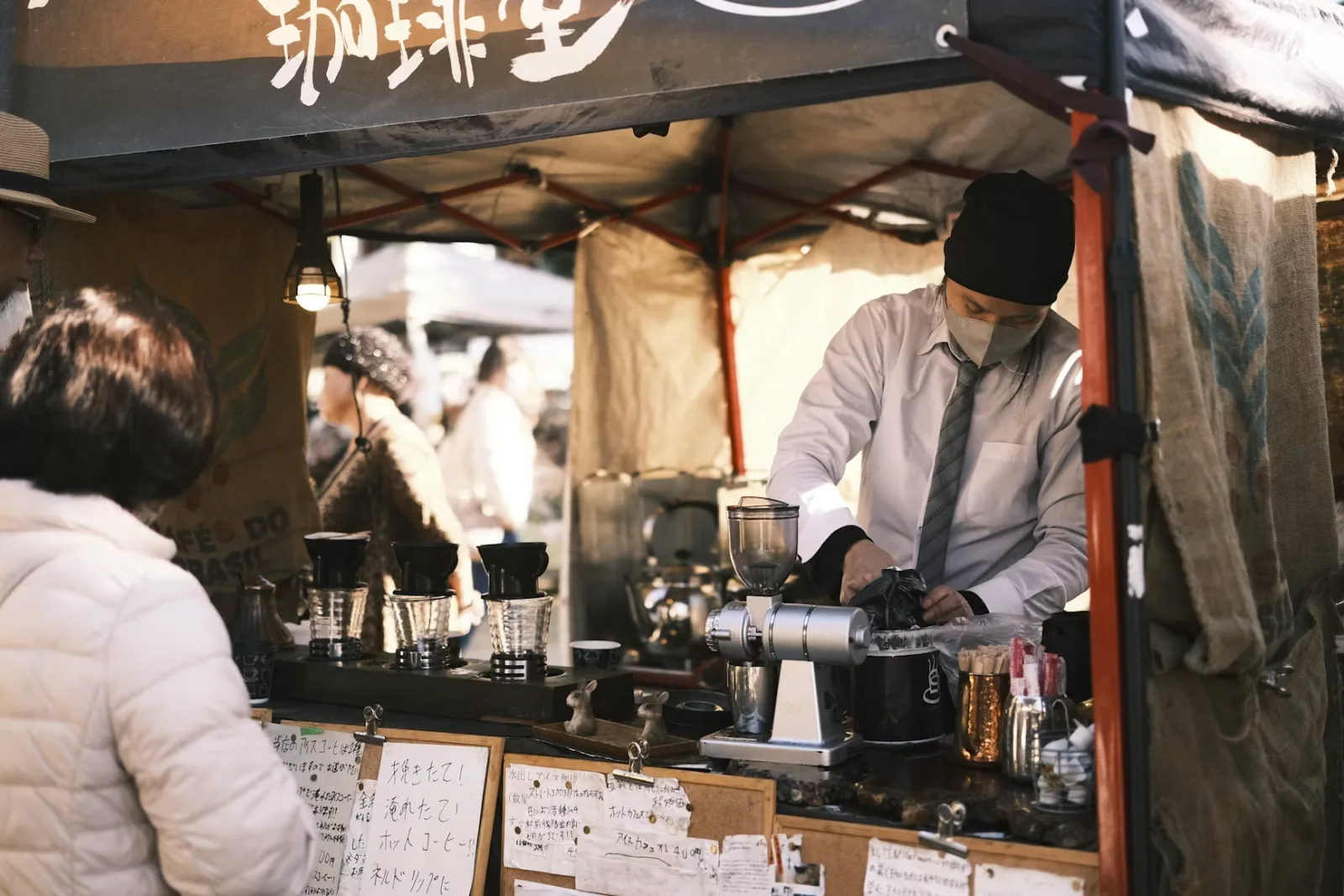 A vendor pouring coffee at a market stall